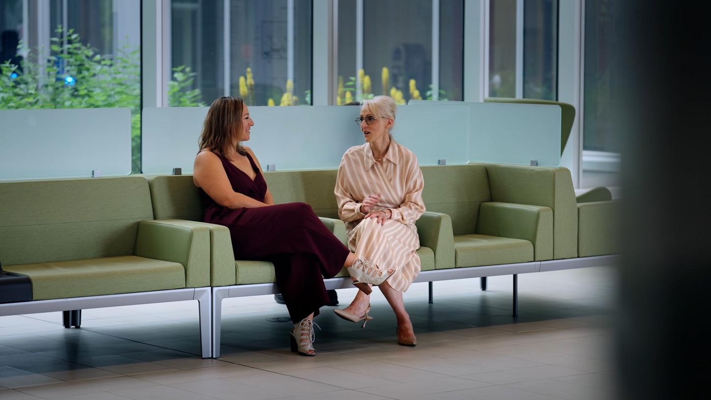 Das Foto zeigt die Krebspatientin Charlotte Kessler und Brenda Hubley, Chief Program Officer von Cancer Care Alberta, wie sie auf einem Sofa sitzen und sich unterhalten.