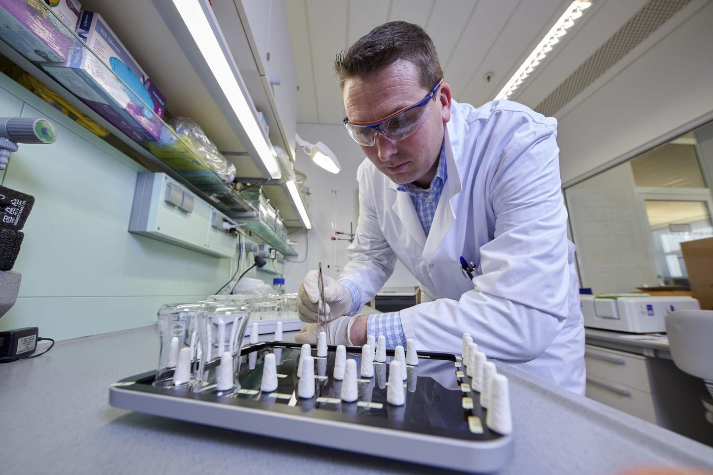 Sebastian Köppl testing a display for its resistance to cleaning agents and disinfectants.