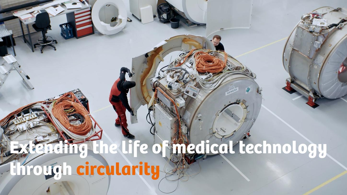 Two people taking apart an MRI device for refurbishment.
