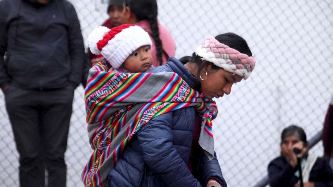 A young mother with her baby on her back queuing for Diospi Suyana hospital 