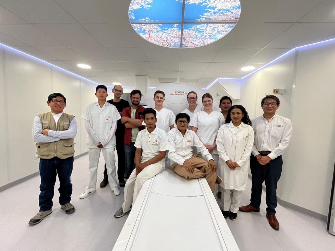 Three healthcare professionals from Uniklinikum Erlangen pose together with Diospi Suyana staff in front of the new scanner 