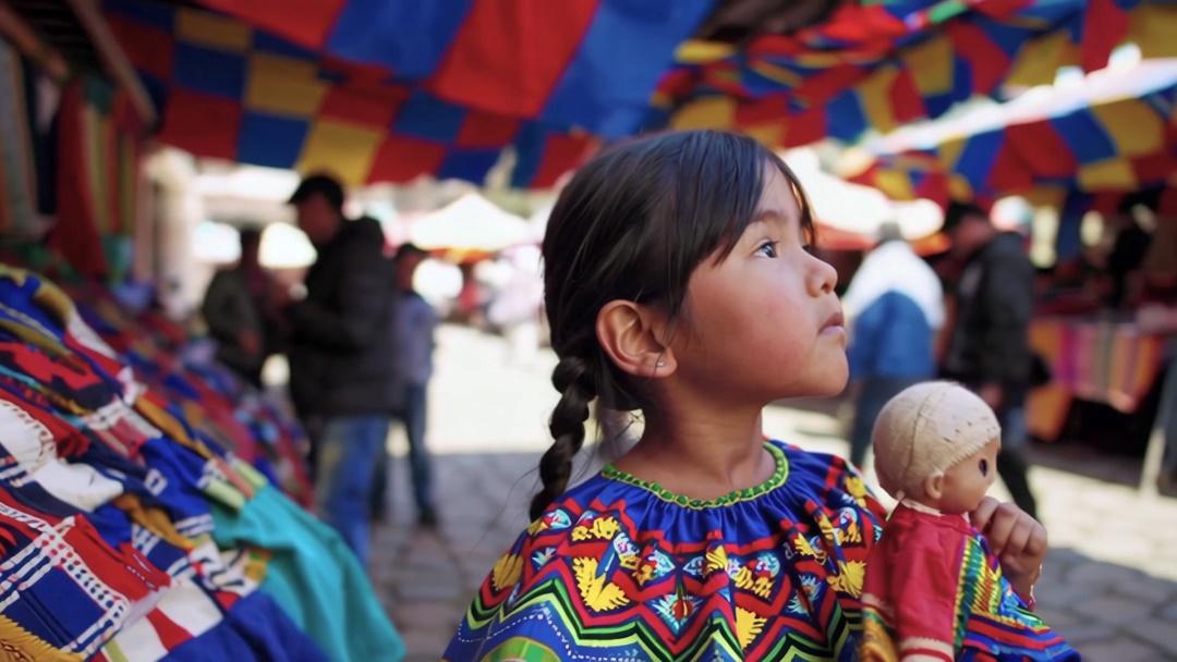 A girl with a doll in her hand at a market in Peru