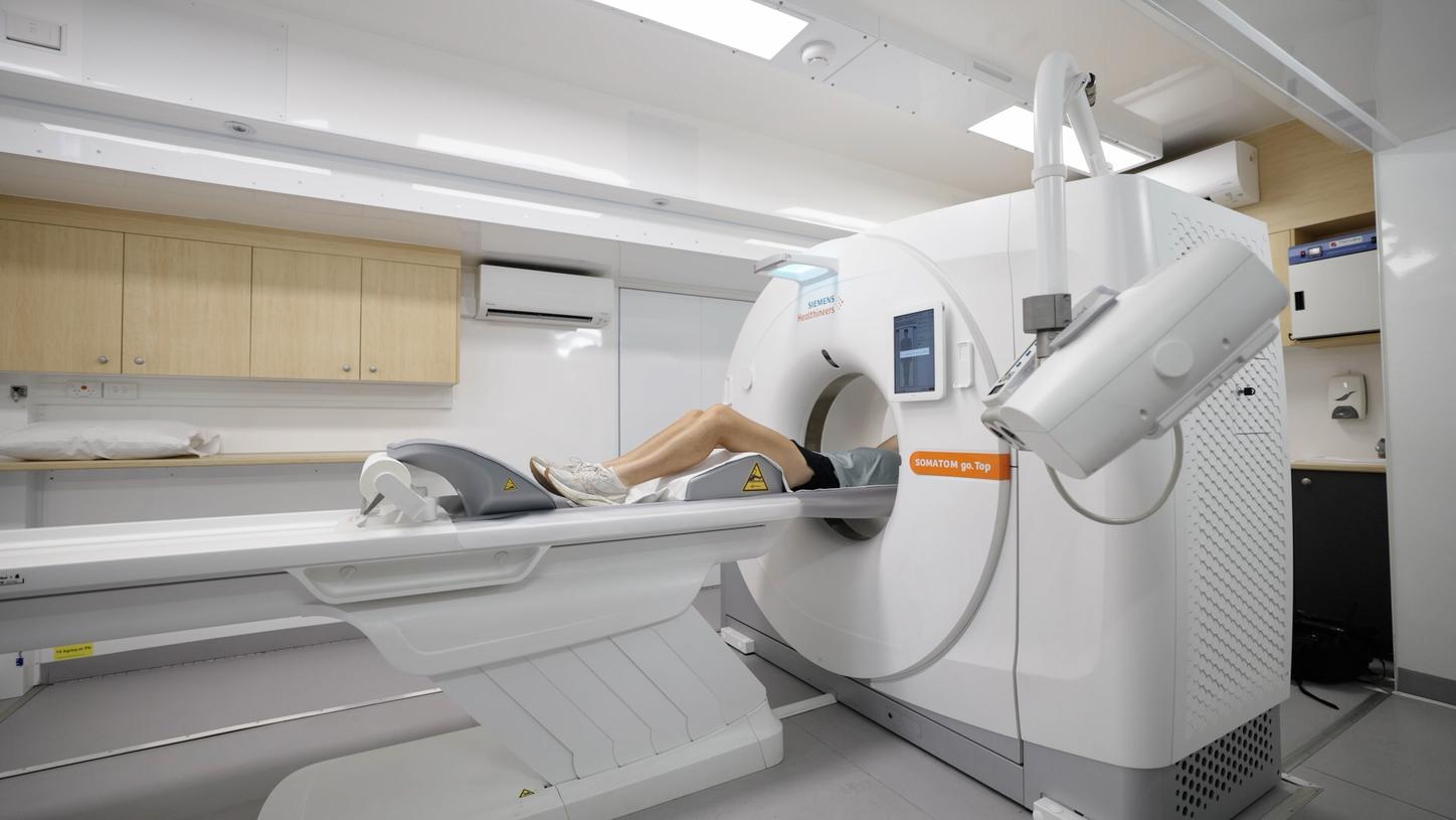 An inside view of a mobile CT truck, showing a CT with a person on the gantry getting scanned.