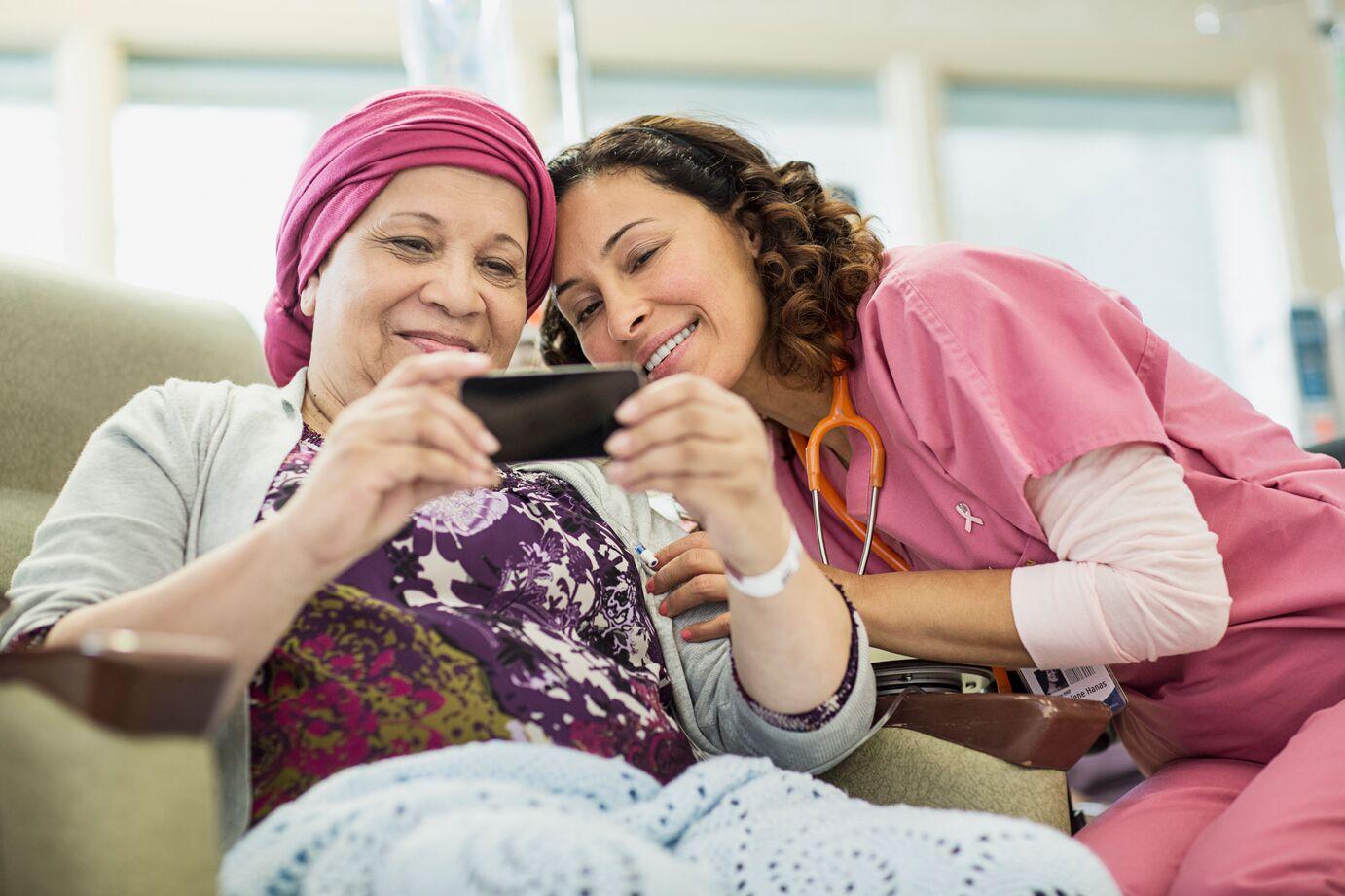 Caretaker and female patient looking into a mobile phone.