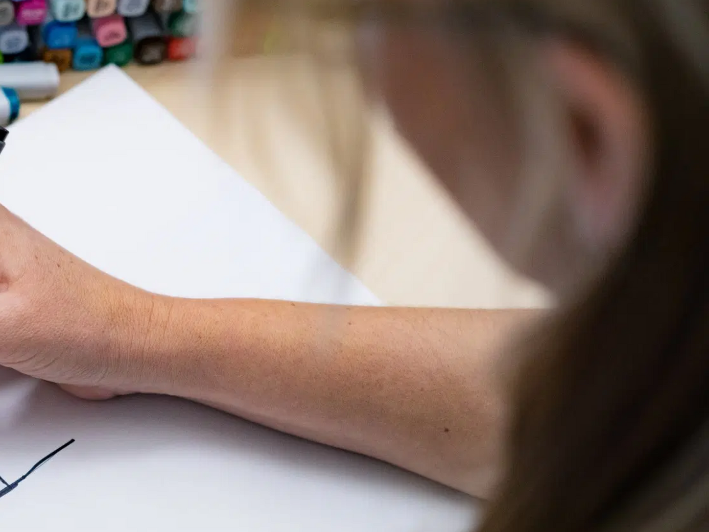 Person, die auf ein weißes Blatt Papier zeichnet.
