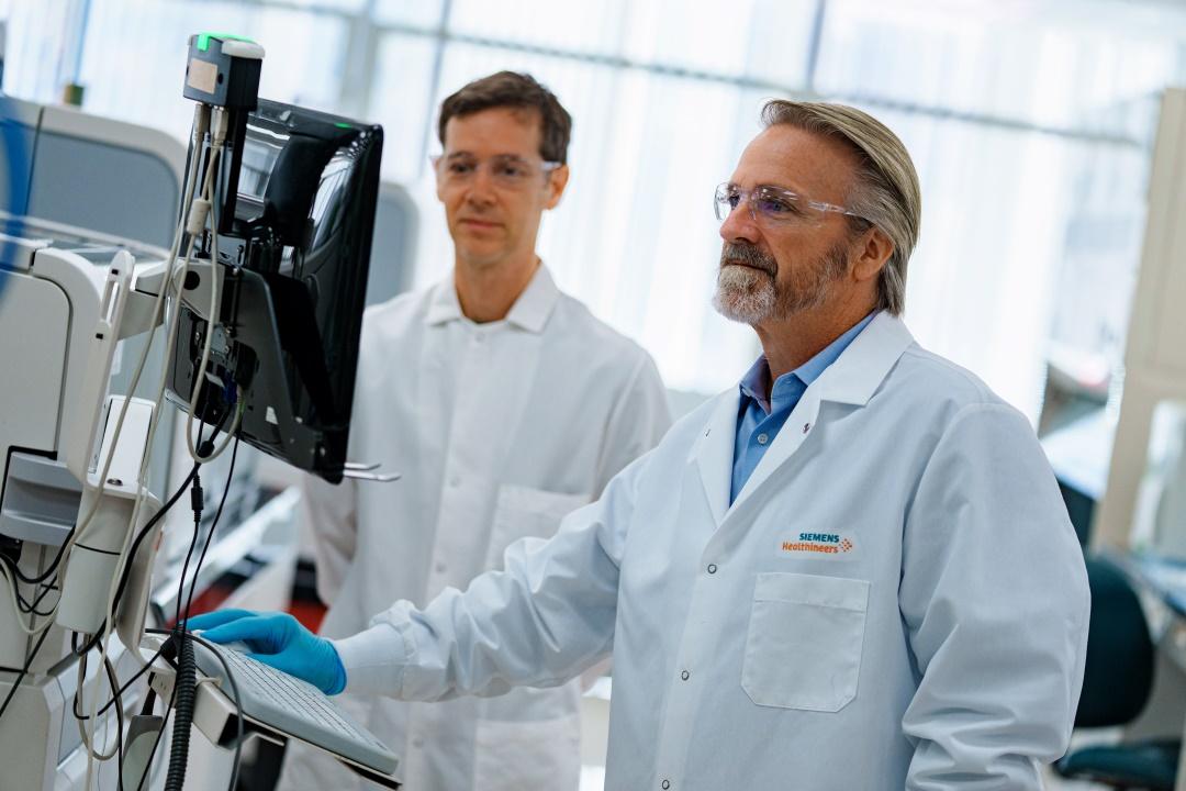 Jim Freeman und ein Kollege schauen auf den Bildschirm eines Analysegeräts.