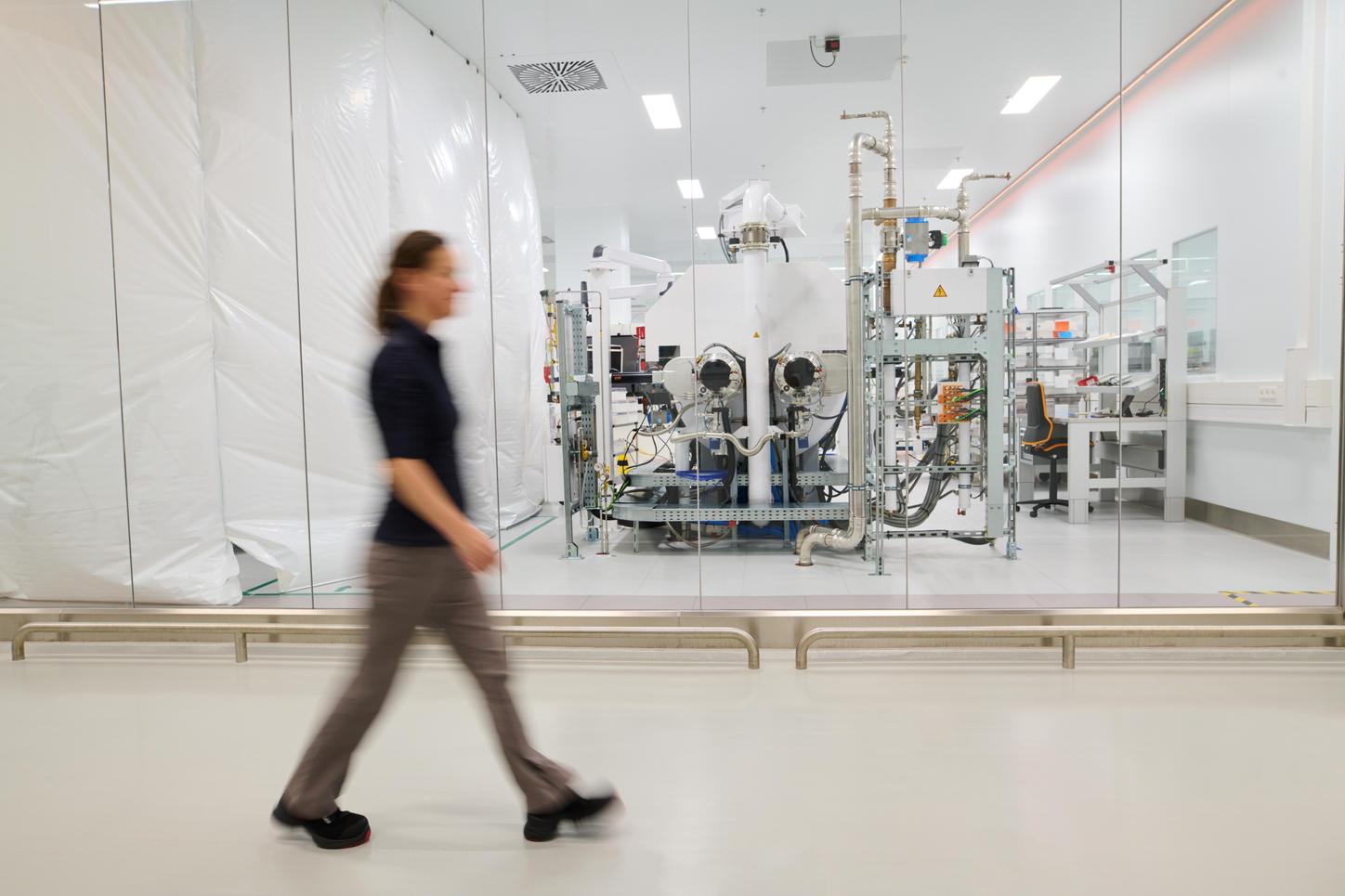 Admission from the HEP Center. In a half-long shot, you can see in the foreground of the picture in the blur how Anja walks along a corridor. Behind a glass wall, you can see part of the X-ray tube production in the background.  