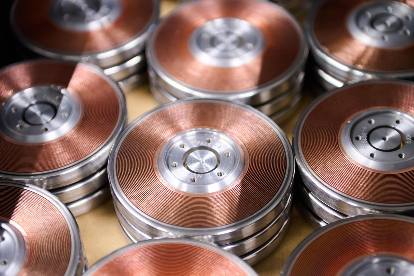 Photo from the X-ray tube recycling in the HEP Center, close-up. Copper-colored anode plates lie in several rows close to each other on a table.  