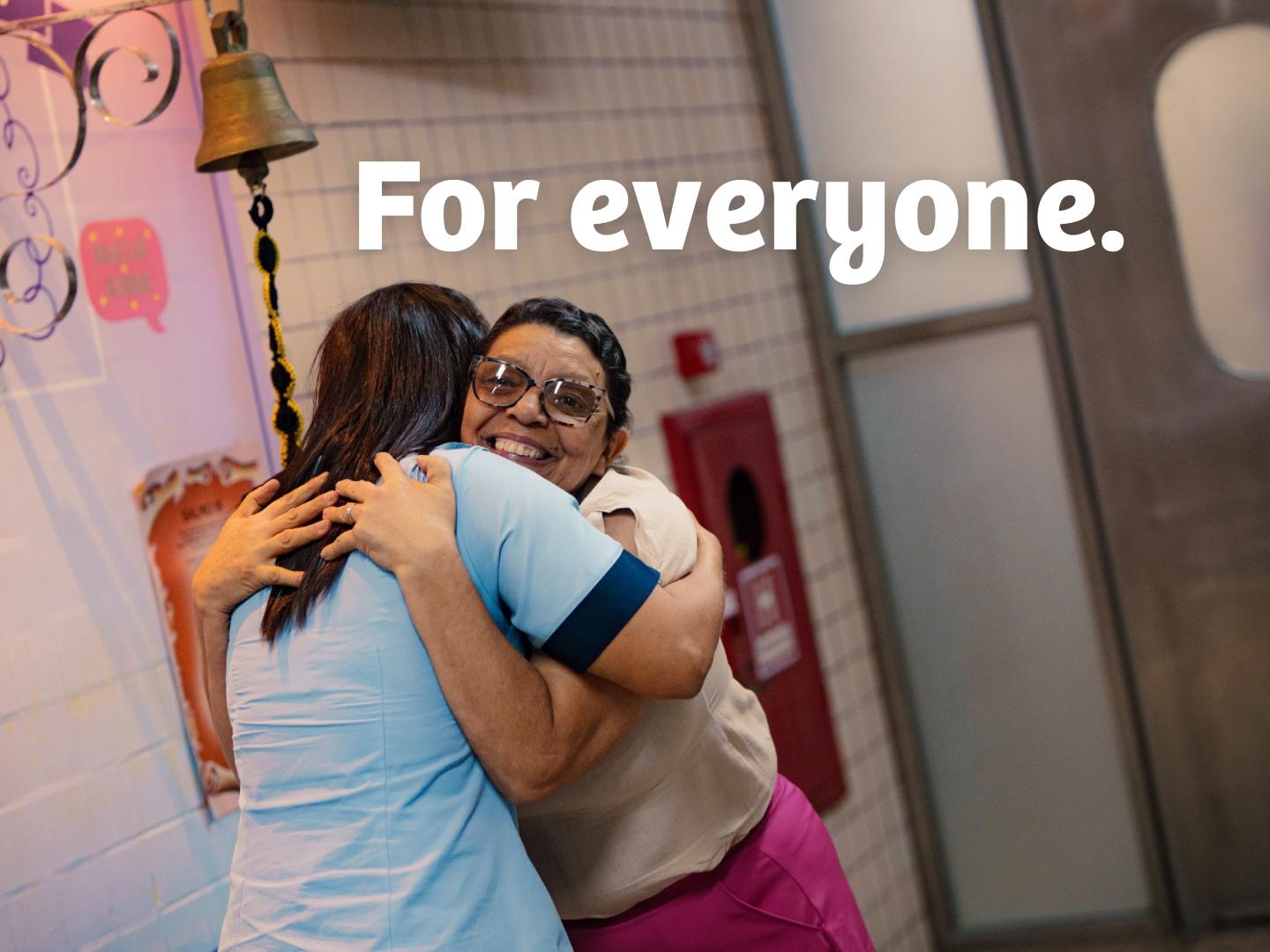 Healthcare worker embracing a smiling woman.