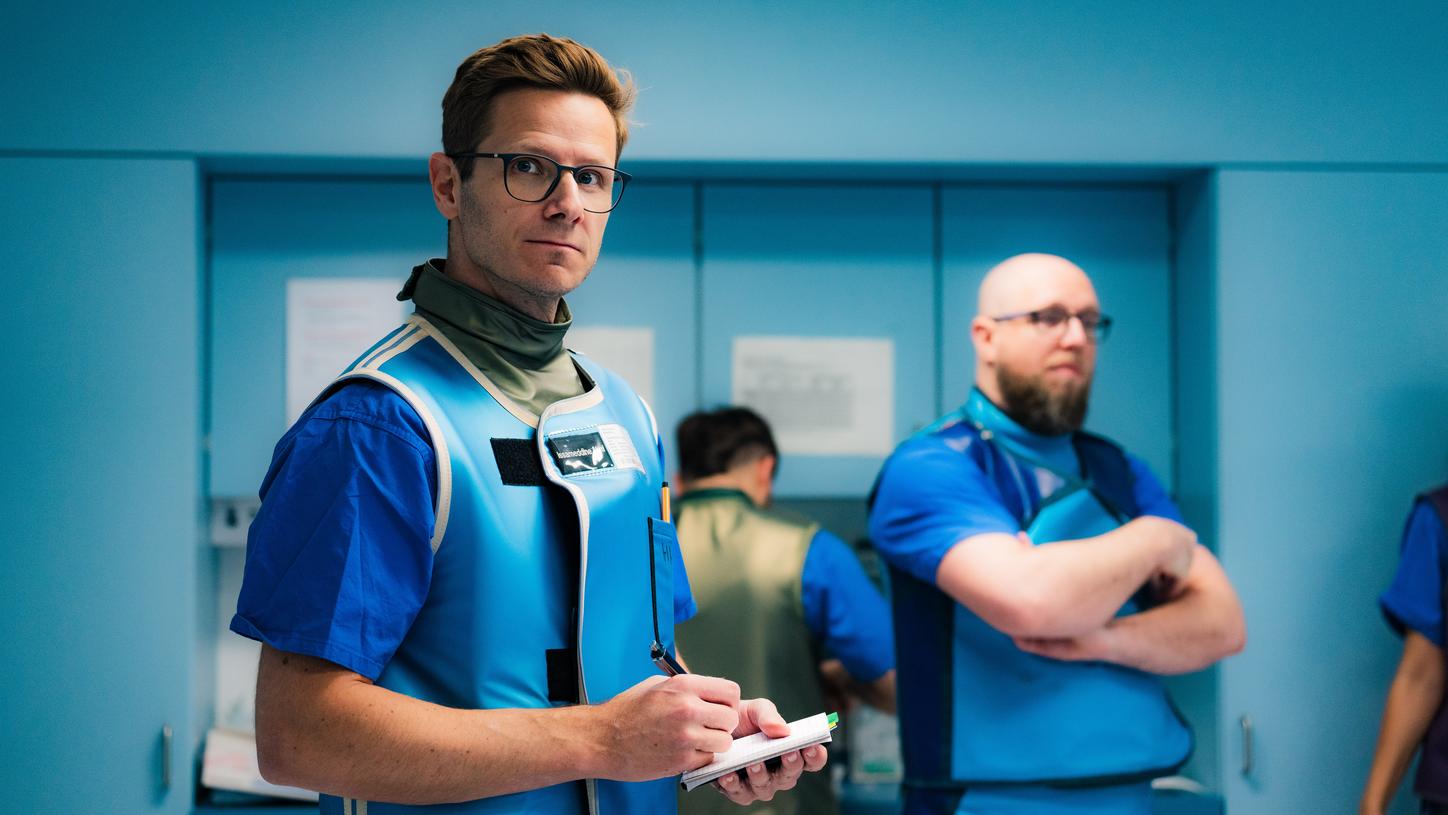 Eine Person in medizinischer Arbeitskleidung hält ein leuchtendes digitales ‚UX‘‑Hologramm, umgeben von dynamischen kreisförmigen und linearen grafischen Elementen, die Technologie und User‑Experience‑Design darstellen.