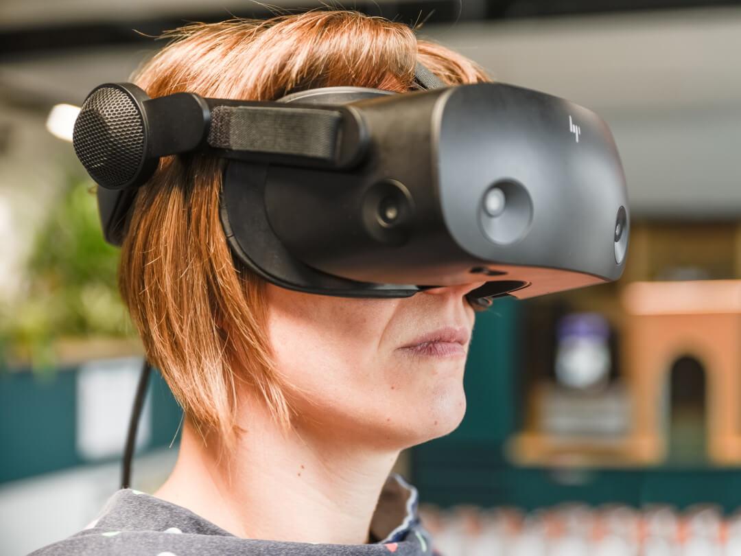 Frau mit roten Haaren, die eine schwarze Virtual-Reality-Brille trägt.